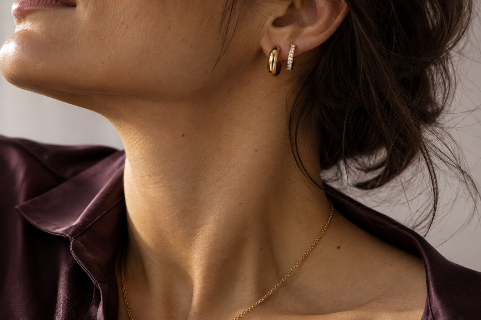Editorial concept of gold and diamond huggies worn with a plum silk shirt